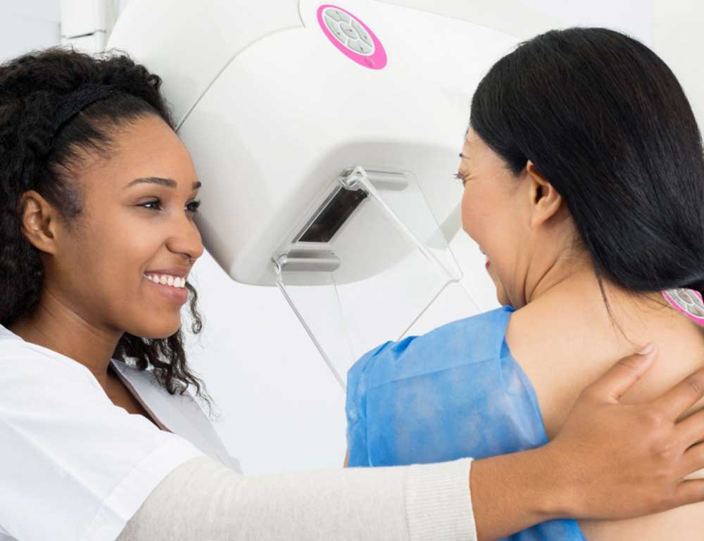 Imaging tech assisting mammogram patient